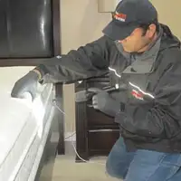 Bed bug inspection technician checking a mattress and bed frame for signs of infestation in Fort Collins, CO