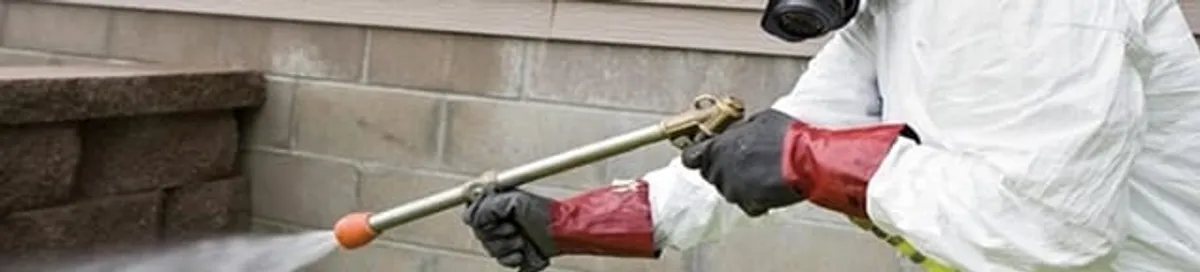 Pest control technician applying exterior insect treatment along a home foundation in Fort Collins, CO