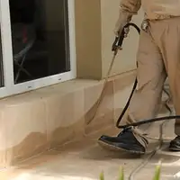 General pest control technician spraying exterior perimeter around a home in Fort Collins, CO