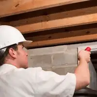 Termite inspection technician checking a basement wall and framing for termite activity in Fort Collins, CO
